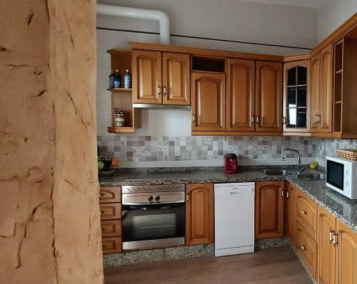 a kitchen with wooden cabinets and a stove top oven at La Plazuela, casa andaluza con patio. in Montoro