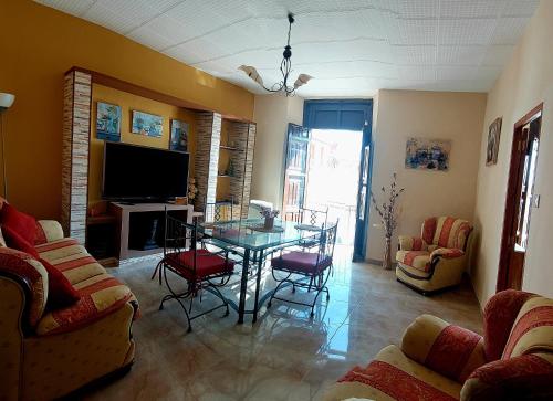 salon ze stołem, krzesłami i telewizorem w obiekcie La Plazuela, casa andaluza con patio. w mieście Montoro