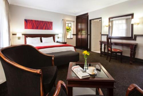 a hotel room with a bed and a table at Court Classique Suite Hotel in Pretoria