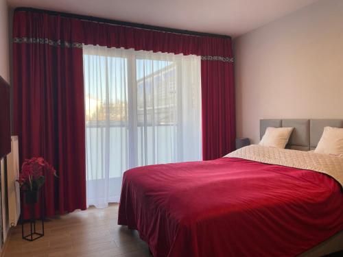 une chambre avec des rideaux rouges et une grande fenêtre dans l'établissement Apartament Kasprowicza, à Kołobrzeg