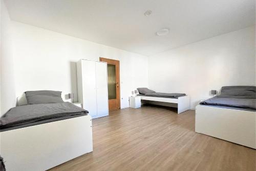 Cette chambre blanche comprend 2 lits et un miroir. dans l'établissement Equipped Apartment in Düren, à Düren