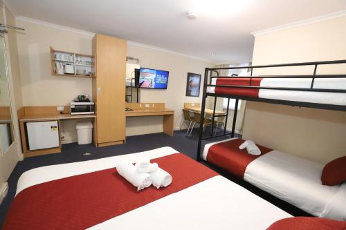 a hotel room with two beds and a desk at Townhouse Motel Cowra in Cowra