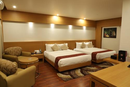 a hotel room with two beds and a couch at Hotel Tea County in Dibrugarh