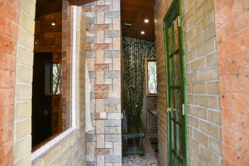 a hallway with a brick wall and a green door at AAA Jermuk rest house in Jermuk