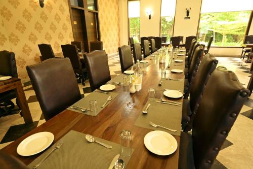a long table with chairs and plates and glasses on it at Clarks Safari Ranthambore in Khilchipur