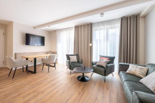 ein Wohnzimmer mit einem Sofa, einem Tisch und Stühlen in der Unterkunft Design Apartments Potsdam - Luise in Potsdam