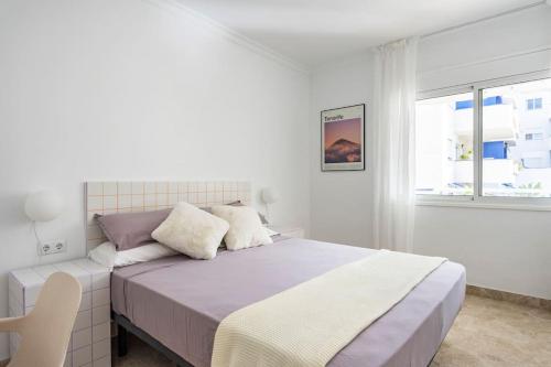 une chambre blanche avec un grand lit et une fenêtre dans l'établissement Apartamento en Los Cristianos urb.Playa Graciosa, à Los Cristianos