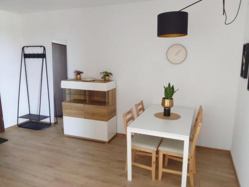 a dining room with a table and chairs and a clock at Complex Apartamenty - Golden in Koszalin