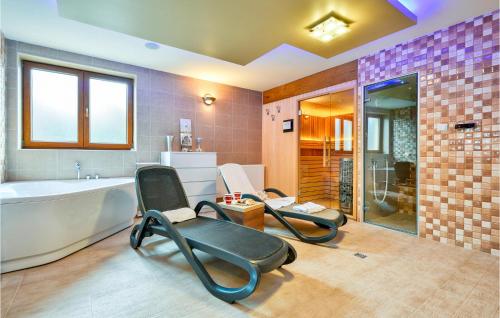 a bathroom with two chairs in front of a bath tub at Cozy Home In Donja Batina With Outdoor Swimming Pool in Donja Batina