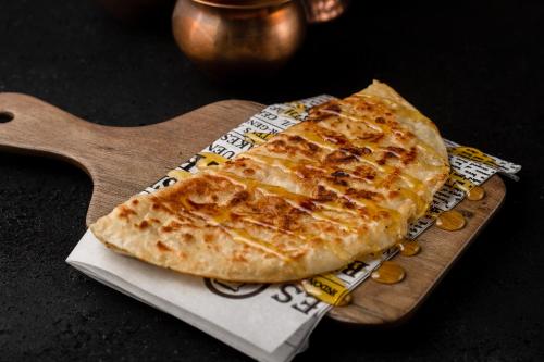 a slice of pizza sitting on a wooden board at Maitrise Hotel Maida Vale - London in London