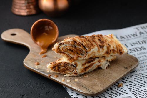 a pastry on a wooden cutting board with a spoon of sauce at Maitrise Hotel Maida Vale - London in London