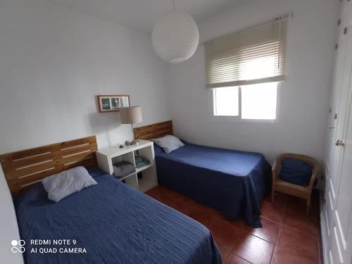 1 dormitorio con 2 camas y ventana en Pareado en Loma Sancti Petri a 900 m de la playa de La Barrosa en Chiclana de la Frontera