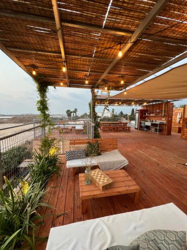 eine Terrasse mit Bänken und Tischen auf einer Terrasse in der Unterkunft Atlit Rooftop Glamping in Atlit