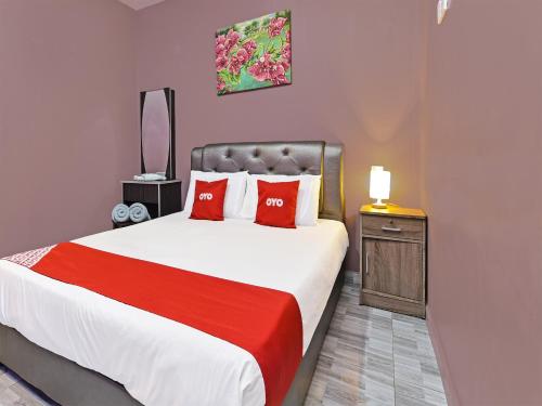 OYO Home 90348 Inspire Rooms في بانتايْ سينانج: غرفة نوم بسرير كبير ومخدات حمراء