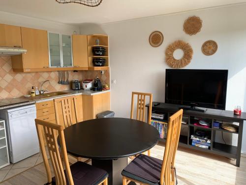 a kitchen with a black table and chairs and a tv at Le Green - Appt Houlgate vue sur le golf in Houlgate