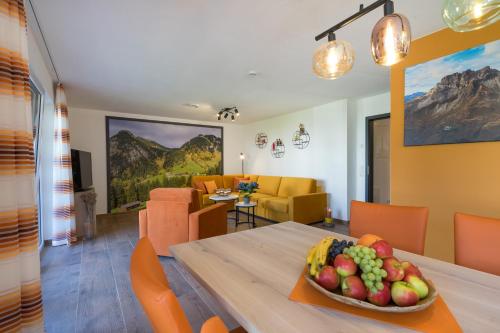 a dining room and living room with a table with a bowl of fruit at Ferienwohnungen Alpentraum - Oberstdorfer Berglodge in Oberstdorf
