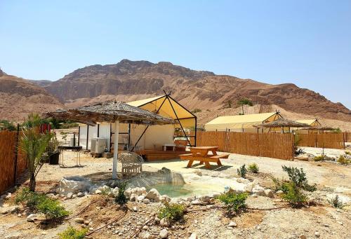 a patio with a table and a picnic table in the desert at TRANQUILO - Dead Sea Glamping in Metsoke Dragot