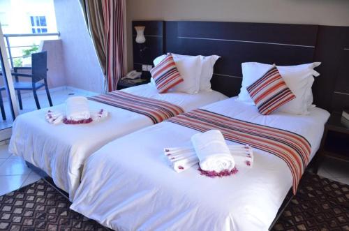 two beds in a hotel room with towels on them at Hotel Al Akha in Sidi Harazem