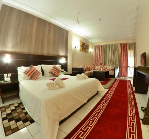 a hotel room with a large bed and a red rug at Hotel Al Akha in Sidi Harazem