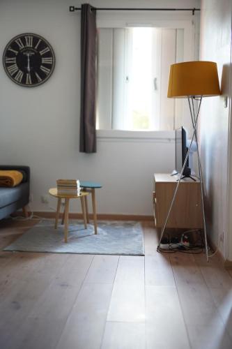 sala de estar con mesa y reloj en la pared en Petit appartement cosy à Troyes en Troyes