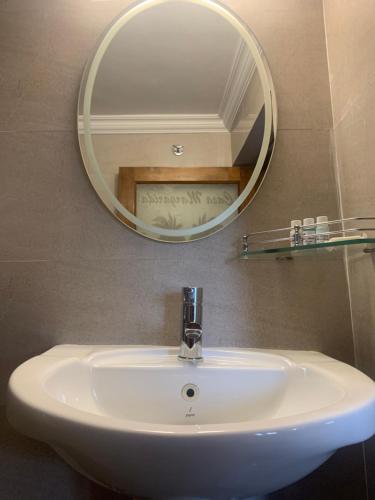 a bathroom sink with a round mirror above it at Casa Margarida in Calangute