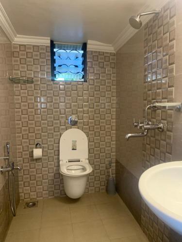 a bathroom with a toilet and a sink and a window at Casa Margarida in Calangute
