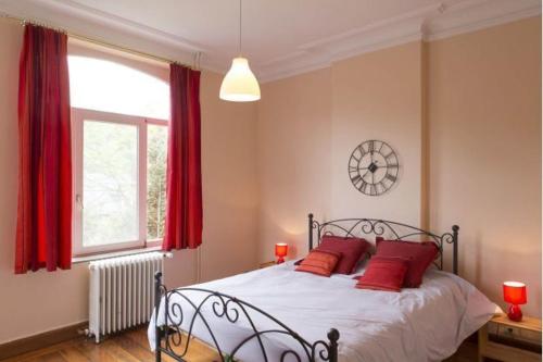 sypialnia z łóżkiem z czerwonymi poduszkami i oknem w obiekcie L'Hermine w mieście Spa