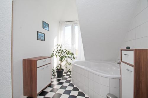 ein Badezimmer mit einer weißen Badewanne und einem schwarz-weiß karierten Boden in der Unterkunft Pension Altes Zollhaus in Norden