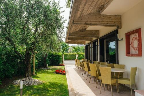 eine Terrasse mit Stühlen, einem Tisch und einem Baum in der Unterkunft Hotel Arena in Sirmione