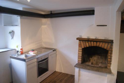 a kitchen with a fireplace in the corner of a room at Charming 3½ room cottage in Valposchiavo in Poschiavo
