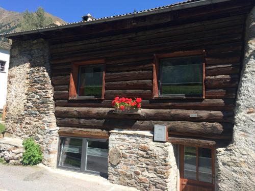 a log cabin with flowers in a window at Charming 3½ room cottage in Valposchiavo in Poschiavo