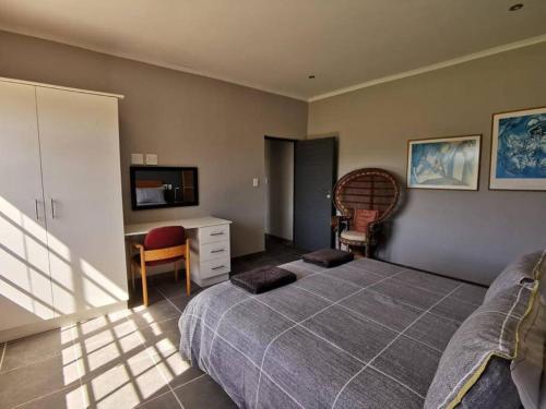 a bedroom with a bed and a desk and a tv at Living The Breede - Weaver Cottage in Malgas