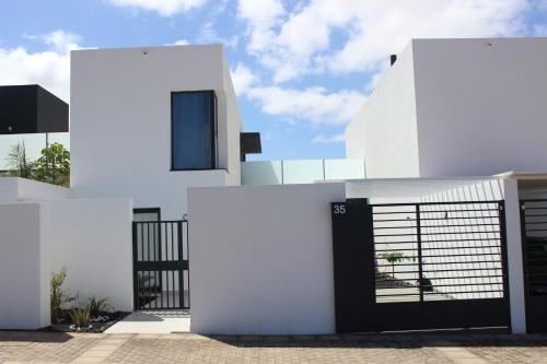 Uma casa branca com um portão preto à frente. em Villa Sol Fuerteventura em La Oliva