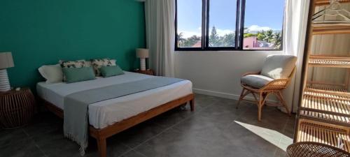 1 dormitorio con 1 cama, 1 silla y 1 ventana en Superbe appartement avec vue mer et montagnes. en Tamarin