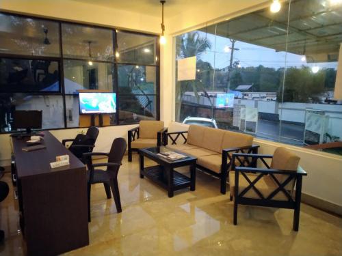 a lobby with a couch and chairs and a tv at Shamrock Inn in Cochin