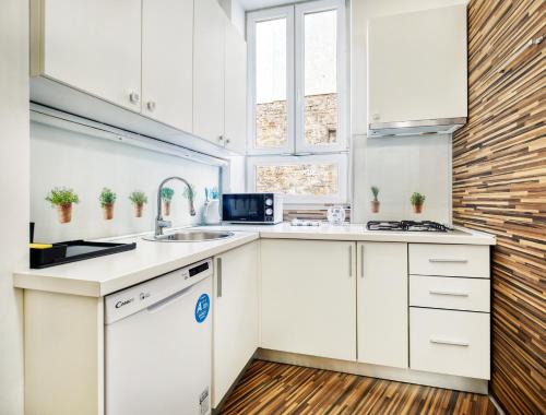 una cocina con armarios blancos y fregadero en Vicus Apartment by Irundo en Zagreb