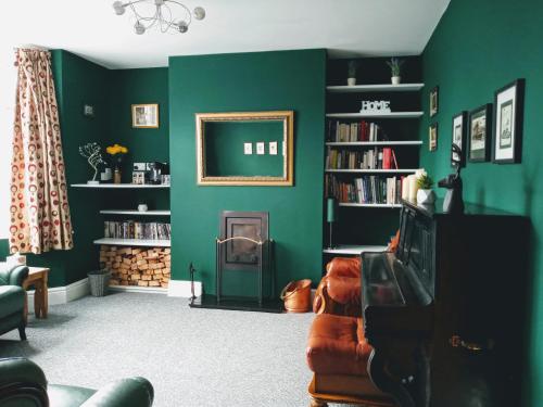 Stunning & Spacious Family Home. Midlands location في كوفينتري: غرفة معيشة مع جدران خضراء وأريكة