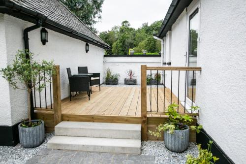 un patio con terrazza in legno, tavolo e sedie. di Glenview Luss a Luss