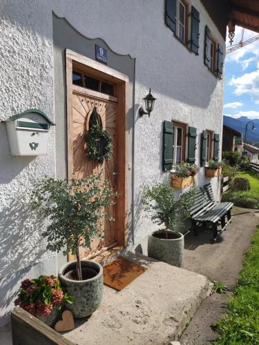 a house with a wooden door and two potted plants at Landhaus im Allgäu in Halblech