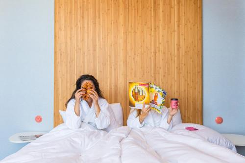 a woman laying in bed reading a book at Vie Via - Your Hotel in Leeuwarden