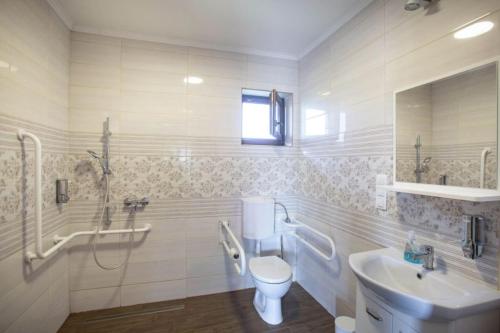 a white bathroom with a sink and a toilet at Kovács tanya - falusi szálláshely in Kunmadaras