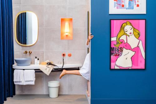 a person standing in a bathroom with a poster of a woman at Vie Via - Your Hotel in Leeuwarden