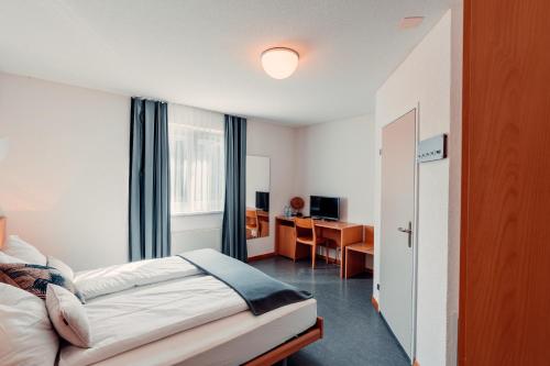 Habitación de hotel con cama y escritorio en Hotel Rössli Luterbach en Luterbach