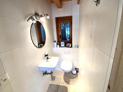 La salle de bains blanche est pourvue d'un lavabo et d'un miroir. dans l'établissement Chalet Les Dalton, Morgins, à Morgins