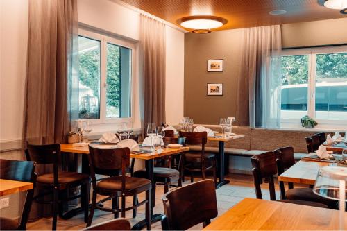 a dining room with tables and chairs and windows at Hotel Rössli Luterbach in Luterbach