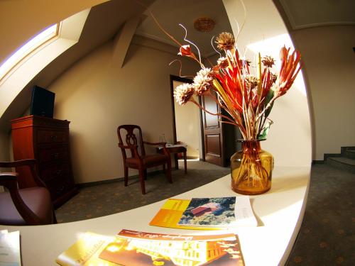 a vase of flowers on a table with a mirror at Rezydencja Pod Zegarem in Trzebinia