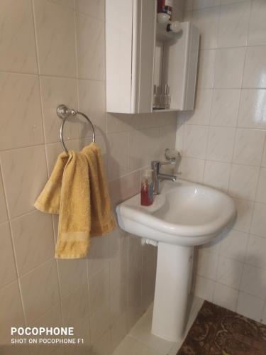 baño con lavabo blanco y toalla en Κεντρικό, άνετο και ζεστό διαμέρισμα, en Kamena Vourla