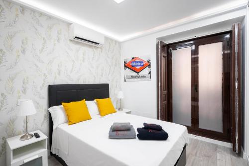 Noviciado Apartment في مدريد: غرفة نوم بسرير ابيض مع مخدات صفراء