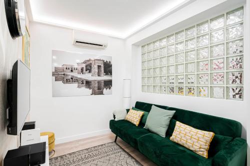 Noviciado Apartment في مدريد: غرفة معيشة مع أريكة خضراء ونافذة كبيرة