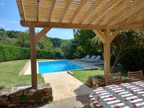 une pergola en bois au-dessus d'une piscine dans une cour dans l'établissement Lalaurie Groupe, à Sauveterre-la-Lémance